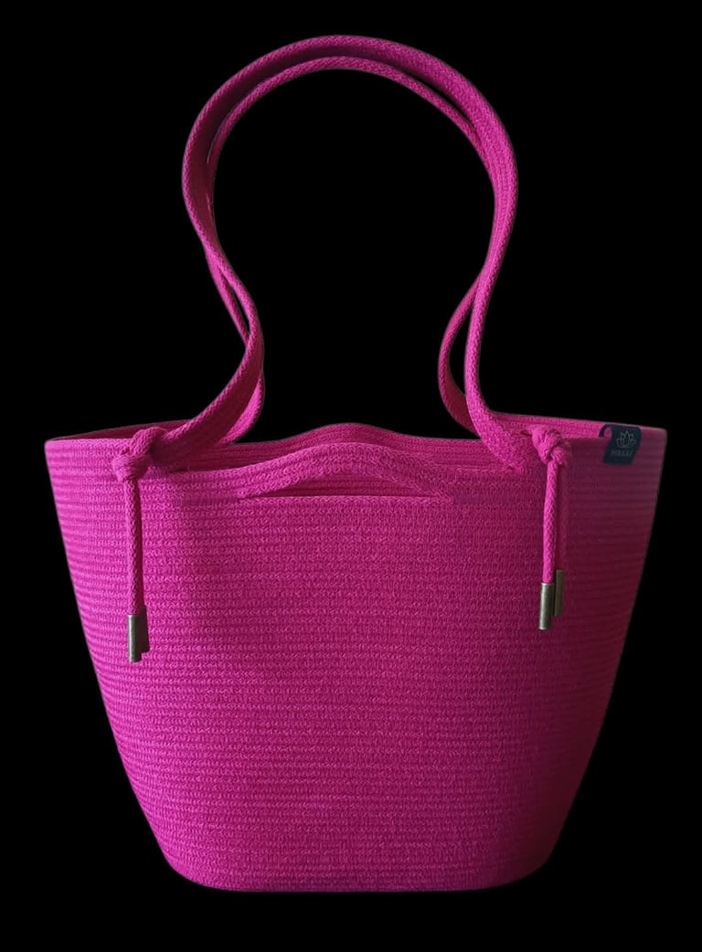 Bright pink woven tote bag with dual handles and metallic accents on a black background