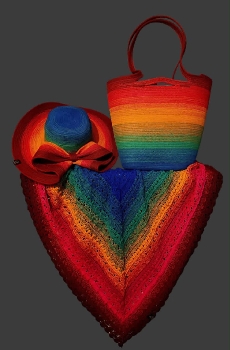 Colorful woven textile collection featuring a heart-shaped bag, matching tote with handles, and a wide-brimmed hat with bow, in rainbow stripes with red accents