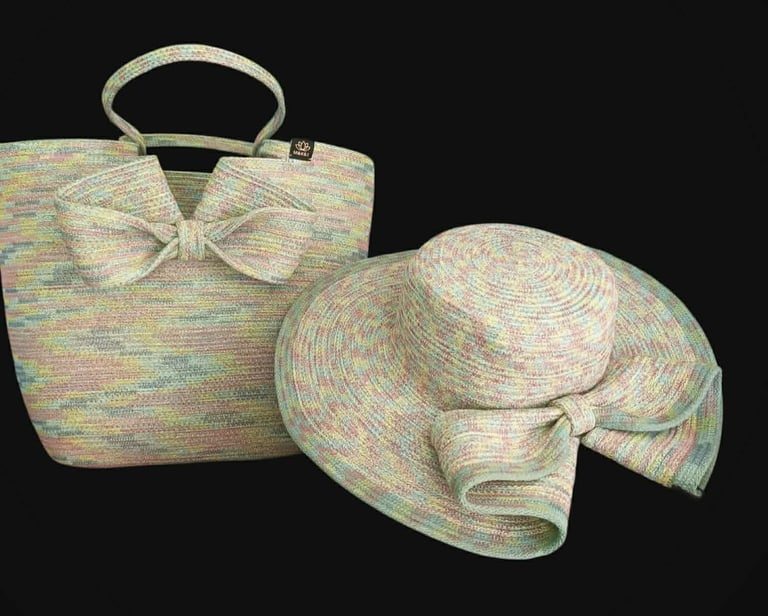 Woven multicolored tote bag with bow detail and matching wide-brimmed sun hat against a black background