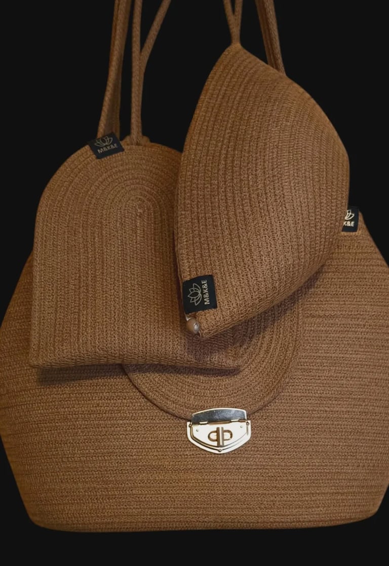 Tan woven tote bag with dual handles and designer logo on black background