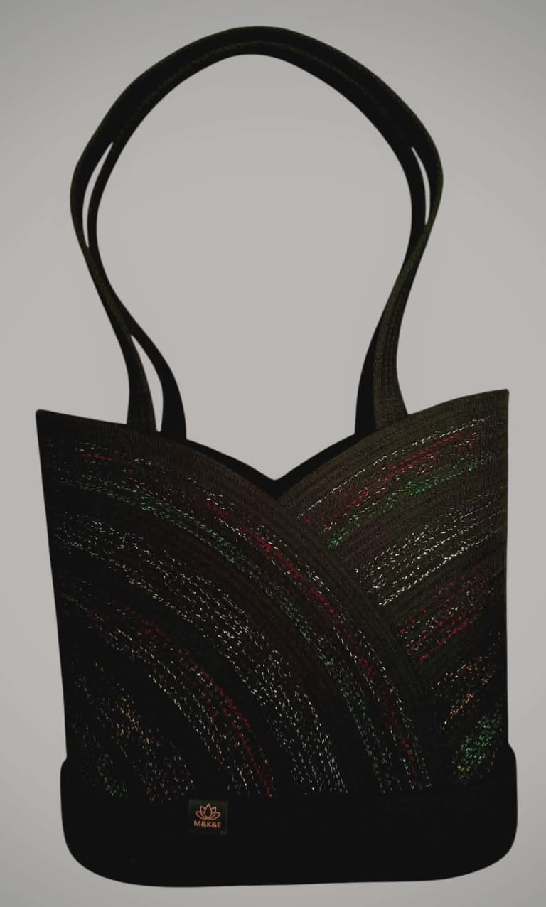 Black tote bag with metallic striped pattern and curved handles displayed against gray background